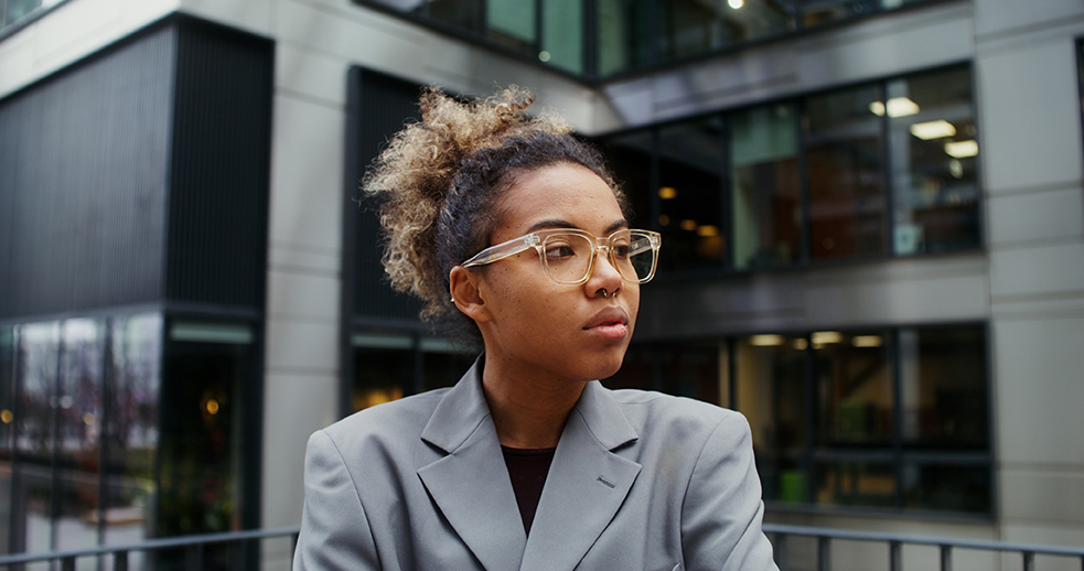 Employee standing outside office building appearing frustrated after whistleblowing retaliation