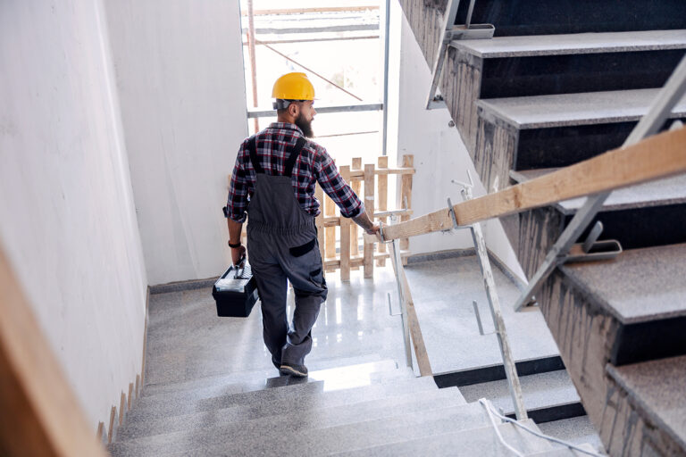 Construction worker walking down stairs with toolbox after job termination