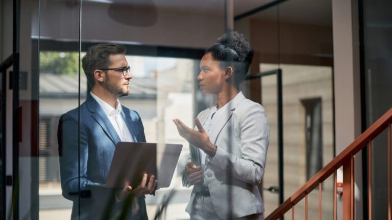 Two professionals discussing how to report workplace harassment internally in a California office setting.