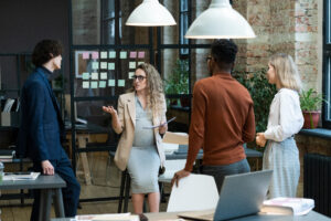 Pregnant employee speaking confidently during a team meeting in a modern office