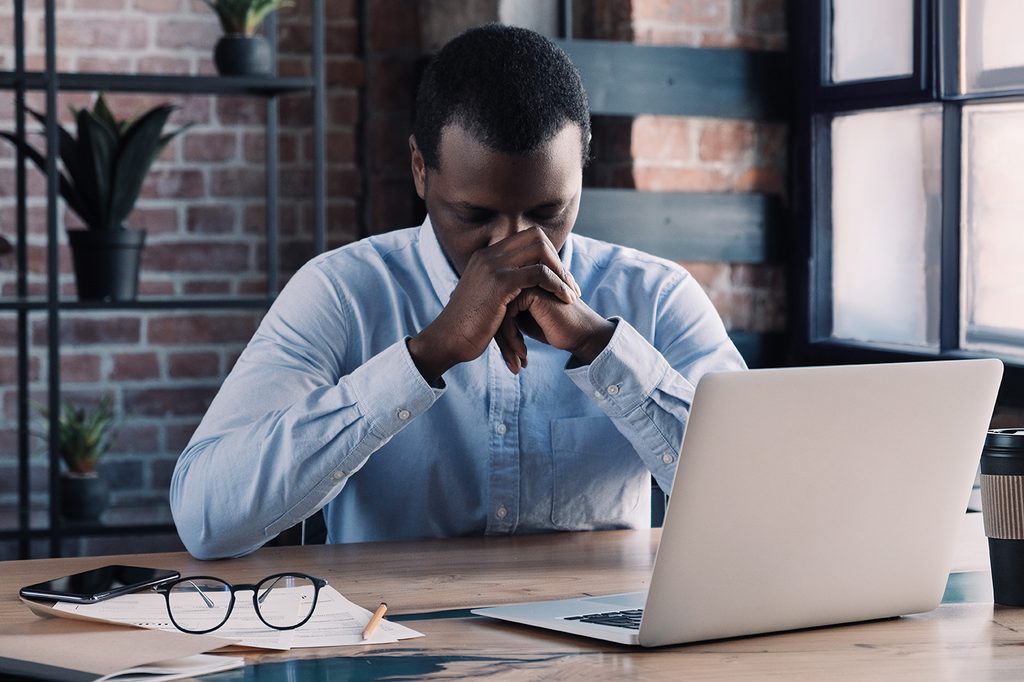 Stressed employee sitting at a desk with his head in his hands, illustrating the pressure of facing constructive dismissal in California