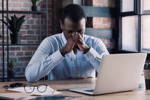 Stressed employee sitting at a desk with his head in his hands, illustrating the pressure of facing constructive dismissal in California