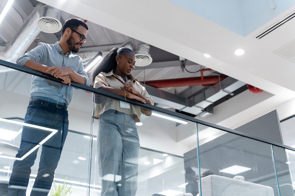 Two coworkers talking in a modern office, illustrating a conversation about reporting sexual harassment at work