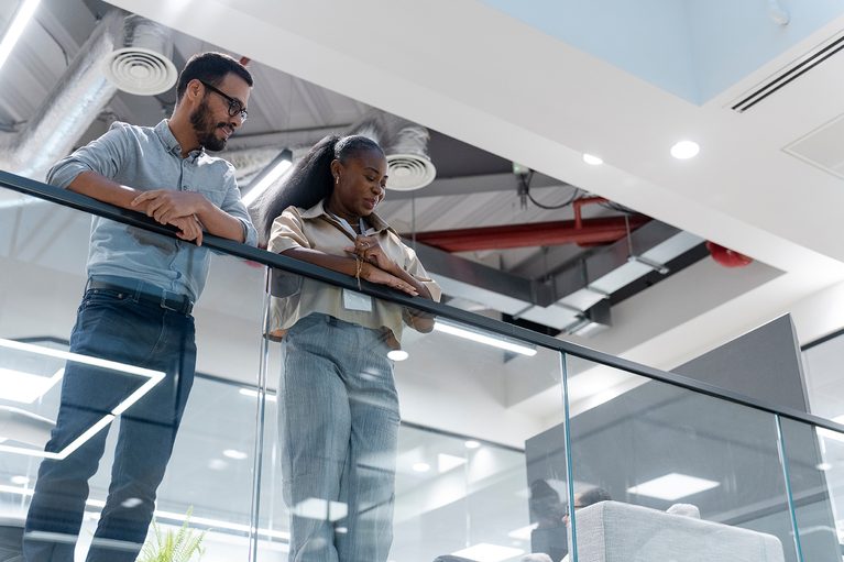 Two coworkers talking in a modern office, illustrating a conversation about reporting sexual harassment at work